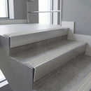 Mill Aluminium raked back aluminium stair nosing 62x55mm with Light Grey Castellated infill, fitted to a concrete step