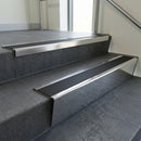 Polished Aluminium raked back aluminium stair nosing 62x55mm with Black Smooth Textured infill, fitted to a concrete step