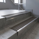 Polished Aluminium raked back aluminium stair nosing 62x55mm with Granite Castellated infill, fitted to a concrete step