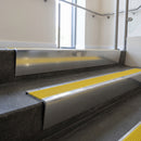 Polished Aluminium raked back aluminium stair nosing 62x55mm with Yellow Castellated infill, fitted to a concrete step