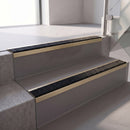 Square edge with ramped back aluminium stair nosing, 70mm tread, coal (black) exterior grip insert, satin gold finish