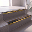 Square edge with ramped back aluminium stair nosing with a dark charcoal Mor Grip insert in mirrorflect gold finish fitted on a retail unit stair finished in grey vinyl