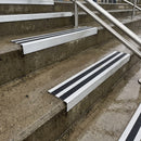 Square edge with ramped back aluminium stair nosing with black gritted exterior grip insert in mill finish finish fitted on covered external concrete steps