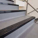 Square edge with ramped back aluminium stair nosing with twin dark charcoal Mor Grip inserts in satin black finish fitted on a leisure centre stair finished in grey safety vinyl