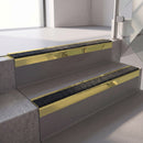 Square edge with ramped back aluminium stair nosing, 70mm tread, coal (black) exterior grip insert, mirrorflect gold finish