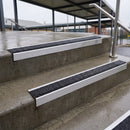 Square edge with ramped back aluminium stair nosing with black gritted exterior grip insert in mill finish finish fitted on covered external concrete steps