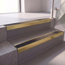 Square edge with ramped back aluminium stair nosing with a dark charcoal Mor Grip insert in satin gold finish fitted on a hospital entrance stair finished in grey safety vinyl