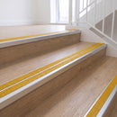 Ramp back twin channel aluminium stair nosing 93 x 38mm in Bright Polished with two Solar textured High Grip inserts, fitted on an indoor oak-effect vinyl staircase