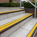 Ramp back twin channel aluminium stair nosing 93 x 38mm in Dark Bronze with two Brimstone gritted Exterior Grip inserts, fitted on wet outdoor entrance steps