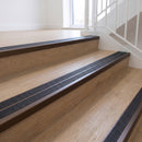 Ramp back twin channel aluminium stair nosing 93 x 38mm in Dark Bronze with two Obsidian textured High Grip inserts, fitted on an indoor oak-effect vinyl staircase