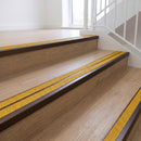 Ramp back twin channel aluminium stair nosing 93 x 38mm in Dark Bronze with two Solar textured High Grip inserts, fitted on an indoor oak-effect vinyl staircase