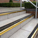 Ramp back twin channel aluminium stair nosing 93 x 38mm in Mirrorflect Gold with two Coal gritted Exterior Grip inserts, fitted on wet outdoor entrance steps