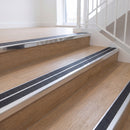 Ramp back twin channel aluminium stair nosing 93 x 38mm in Mirrorflect Silver with two Obsidian textured High Grip inserts, fitted on an indoor oak-effect vinyl staircase
