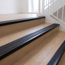 Ramp back twin channel aluminium stair nosing 93 x 38mm in Satin Black with two Obsidian textured High Grip inserts, fitted on an indoor oak-effect vinyl staircase