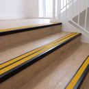 Ramp back twin channel aluminium stair nosing 93 x 38mm in Satin Black with two Solar textured High Grip inserts, fitted on an indoor oak-effect vinyl staircase