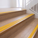 Ramp back twin channel aluminium stair nosing 93 x 38mm in Satin Bronze with two Solar textured High Grip inserts, fitted on an indoor oak-effect vinyl staircase