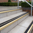 Ramp back twin channel aluminium stair nosing 93 x 38mm in Satin Gold with two Coal gritted Exterior Grip inserts, fitted on wet outdoor entrance steps