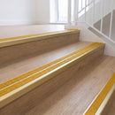 Ramp back twin channel aluminium stair nosing 93 x 38mm in Satin Gold with two Solar textured High Grip inserts, fitted on an indoor oak-effect vinyl staircase