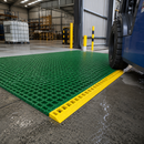 Yellow GRP anti-slip ramp section installed with green fibreglass grating panels in warehouse