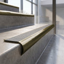 Antique Brass finish - solid brass raked back stair nosing with CarbiGrip - Italian Marble insert fitted on concrete steps