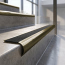 Antique Brass finish - solid brass raked back stair nosing with CarbiGrip - Obsidian insert fitted on concrete steps