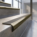Antique Brass finish - solid brass raked back stair nosing with CarbiGrip - Pebble insert fitted on concrete steps