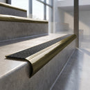 Antique Brass finish - solid brass raked back stair nosing with CarbiGrip - Speckled Obsidian insert fitted on concrete steps