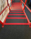 Red GRP anti-slip stair nosings on the front edge of grey gritted steps on a steel access stair