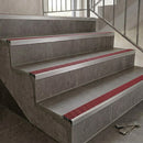 Slimline aluminium stair nosings with red anti-slip inserts on grey tiled staircase