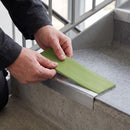 Replacement Apple Green PVC insert strip being pressed into the channel of an aluminium stair nosing