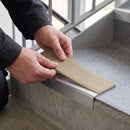 Replacement Beige PVC insert strip being pressed into the channel of an aluminium stair nosing