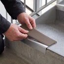 Replacement Brown PVC insert strip being pressed into the channel of an aluminium stair nosing