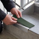 Replacement Dark Green PVC insert strip being pressed into the channel of an aluminium stair nosing