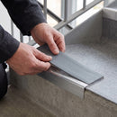 Replacement Mid Grey PVC insert strip being pressed into the channel of an aluminium stair nosing
