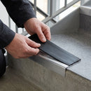 Replacement Premium Black PVC insert strip being pressed into the channel of an aluminium stair nosing