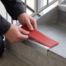 Replacement Red PVC insert strip being pressed into the channel of an aluminium stair nosing