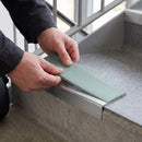 Replacement Sage Green PVC insert strip being pressed into the channel of an aluminium stair nosing