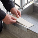Replacement White PVC insert strip being pressed into the channel of an aluminium stair nosing