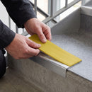 Replacement Yellow PVC insert strip being pressed into the channel of an aluminium stair nosing