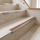 Retro-fit stainless steel stair nosing with NB Nut Brown RAL 8007 R11 grit tread on cream travertine-look tiled stairs