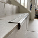 Retro-fit stainless steel stair nosing with clear anti-slip tread wrapping over the edge of an existing tiled step
