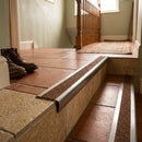 Retro-fit stainless steel stair nosing with nut brown anti-slip tread on terracotta tiled steps in a home hallway