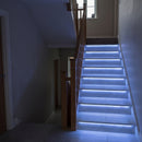 RGB LED tape glowing blue under the nosings of a tiled staircase in a modern interior