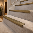 Ribbed antique brass stair nosings on beige carpeted stairs in a classic hallway
