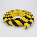 Coiled five metre length of black and yellow striped right angle foam edge guard on a plain grey background