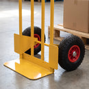 Close-up of the fixed yellow steel toe plate, wheel guard and pneumatic wheel with red hub on a 200kg sack truck on a warehouse floor