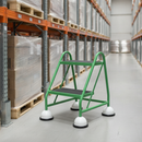 Green mobile safety steps with twin handrail in a warehouse aisle