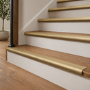 Satin brass ribbed stair nosings on oak treads with white risers in a bright hallway