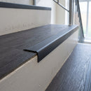 Dark grey self adhesive stair nosing fitted to a dark LVT step in a communal stairwell