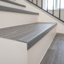 Grey self adhesive stair nosing fitted to a vinyl step edge in a light commercial stairwell